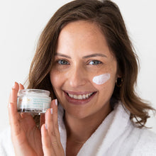 Load image into Gallery viewer, Smiling woman holding Lavido Age Away Replenishing Cream with a dab of cream on her cheek