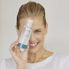 Load image into Gallery viewer, Smiling woman holding a bottle of Lavido Micellar Cleansing Water over one eye