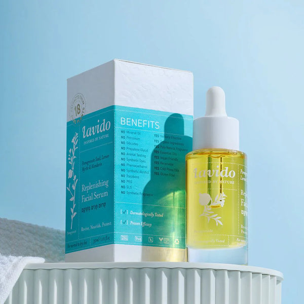 Lavido Replenishing Facial Serum dropper bottle beside its blue box on a white pedestal
